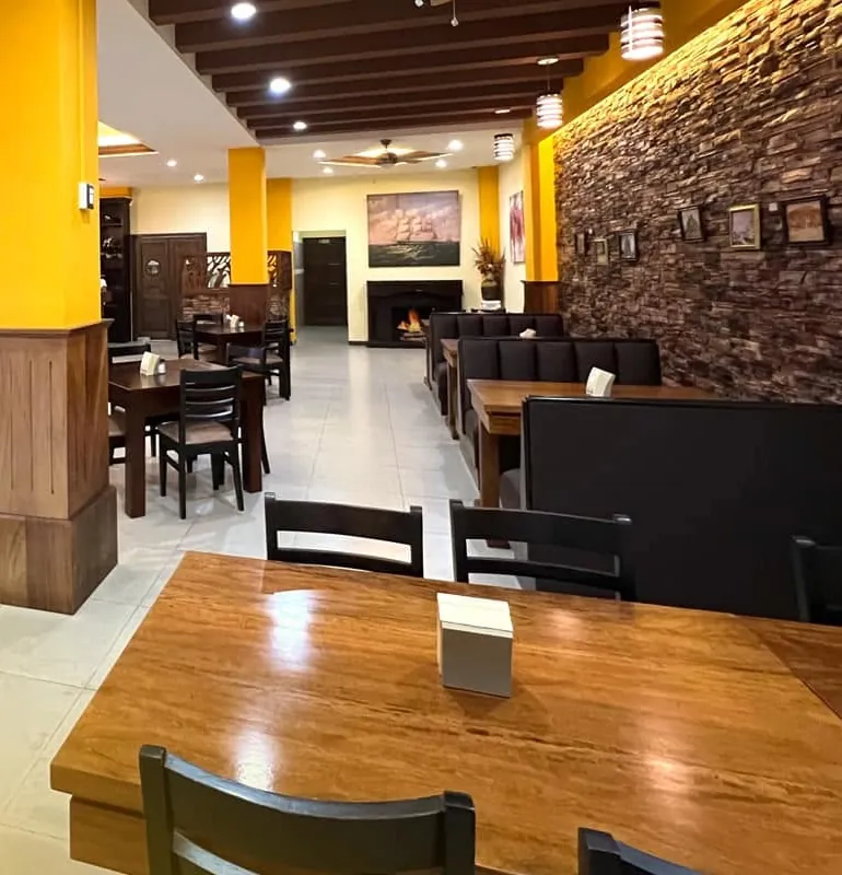 Salón principal con mesas de madera y pared de piedra